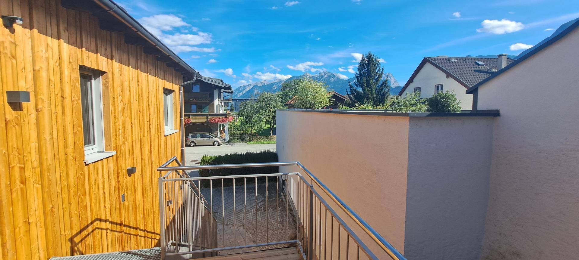 Blick von der Außentreppe auf die umliegende Berglandschaft und benachbarte Gebäude.