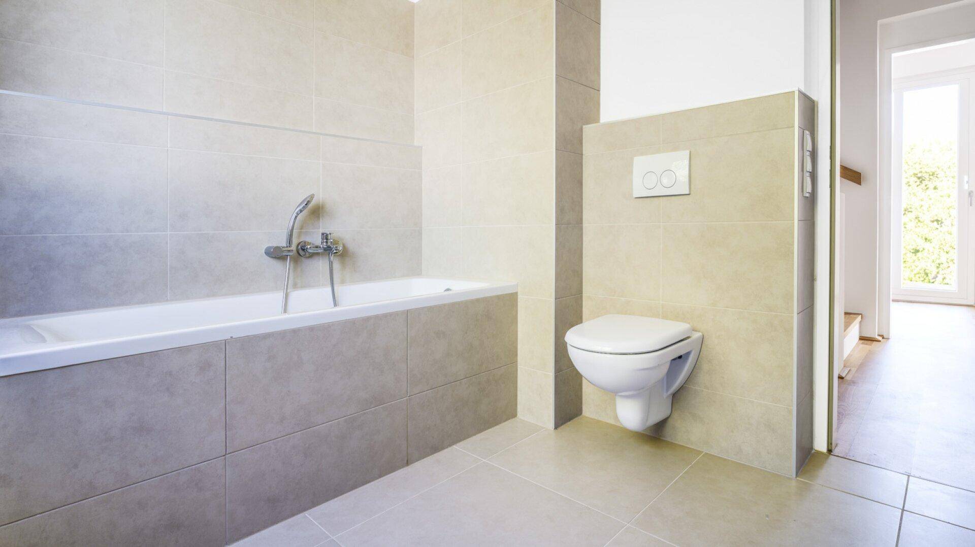 Modernes Badezimmer mit Badewanne, wandhängendem WC und hellen Fliesen.