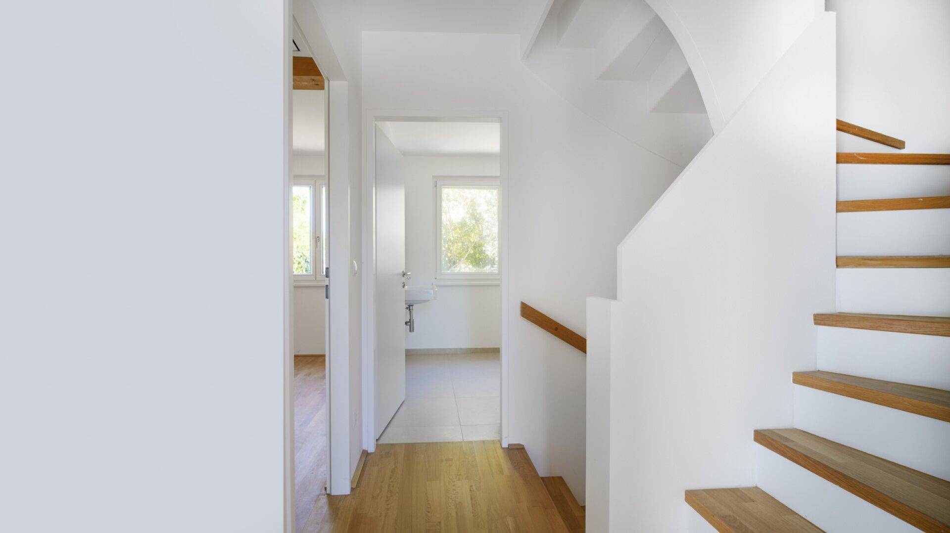 Heller Flur mit Parkettboden und Treppe, der zu weiteren Räumen führt.