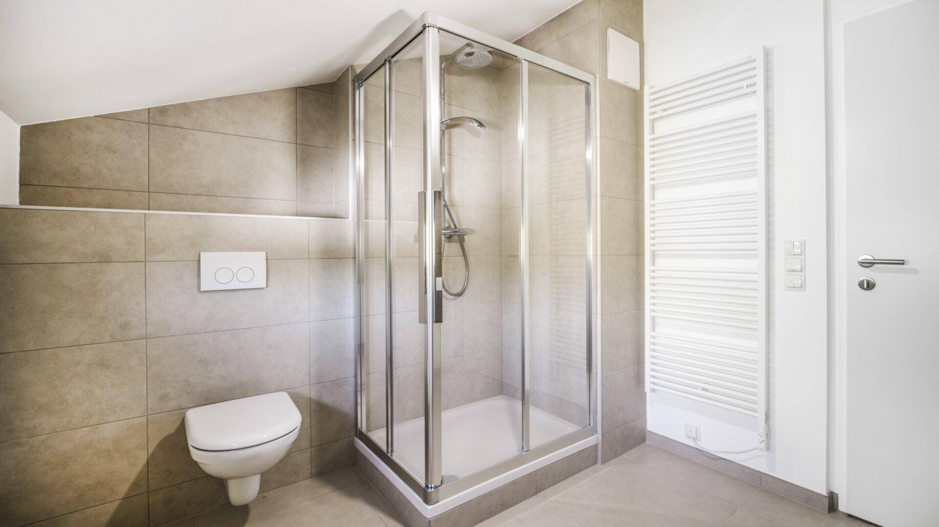 Modernes Badezimmer mit Duschkabine, wandhängendem WC und beheiztem Handtuchhalter.