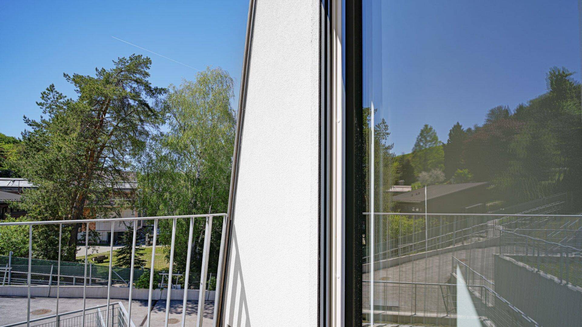 Balkon mit Metallgeländer und Blick auf die grüne Umgebung und weitere Gebäude.