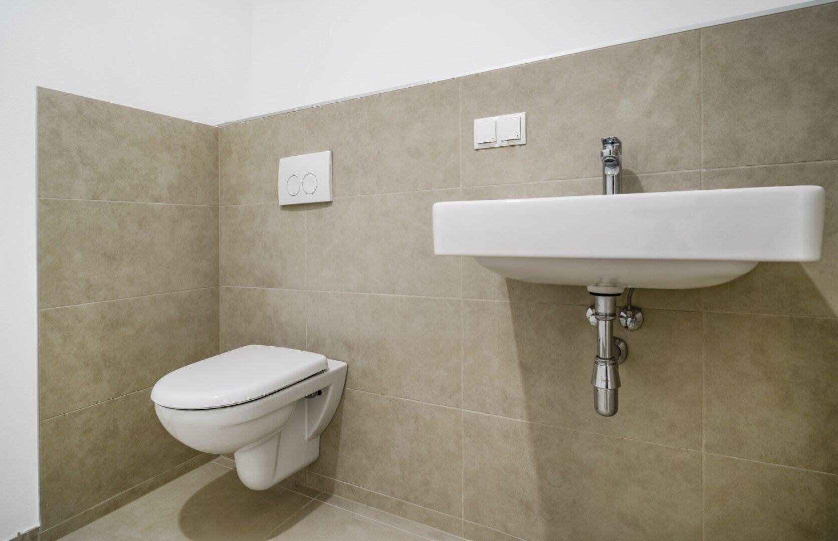Modernes Gäste-WC mit Wand-WC, Waschbecken und beigefarbenen Fliesen an den Wänden.