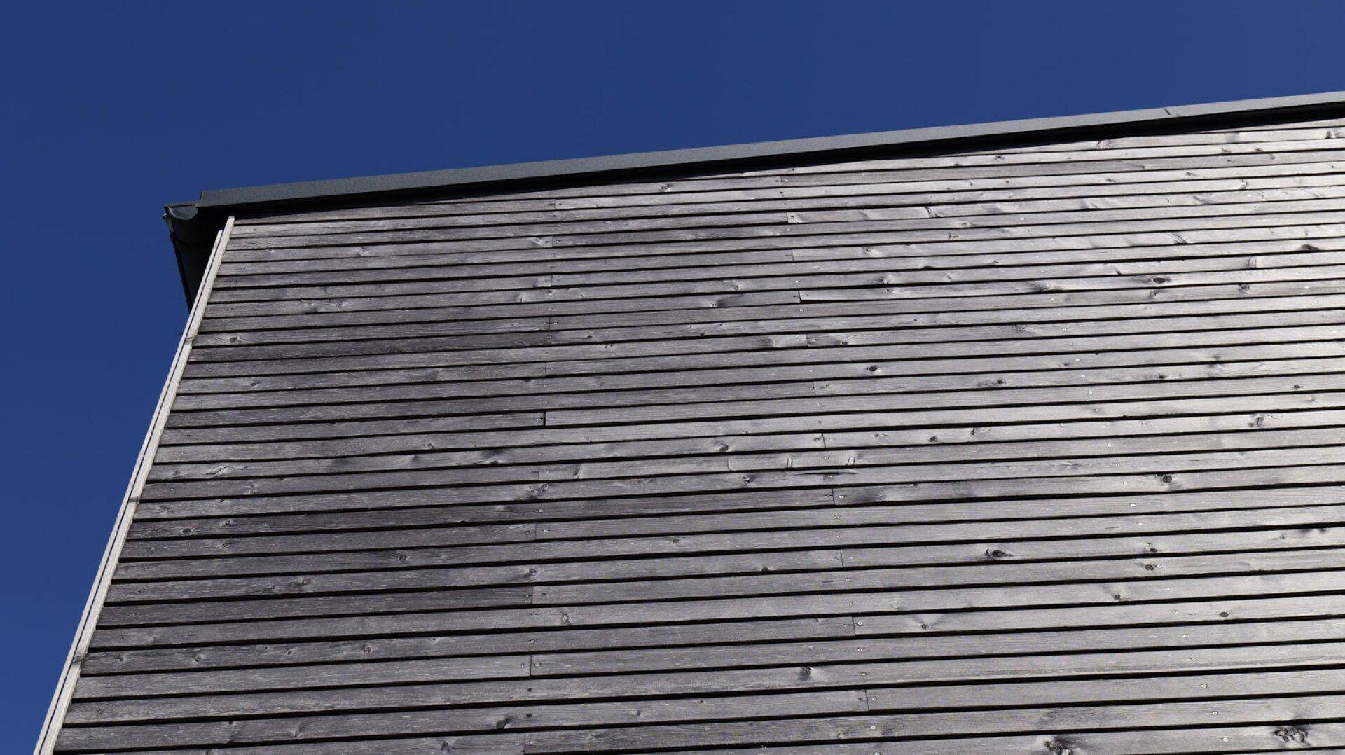 Detailansicht einer modernen Holzfassade unter klarem blauem Himmel.