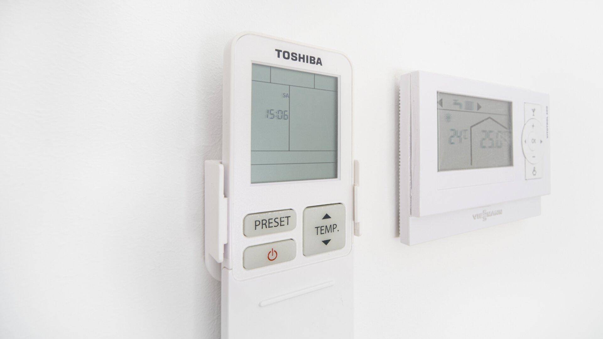 Moderne Steuerungselemente für Klimaanlage und Heizung an einer weißen Wand.