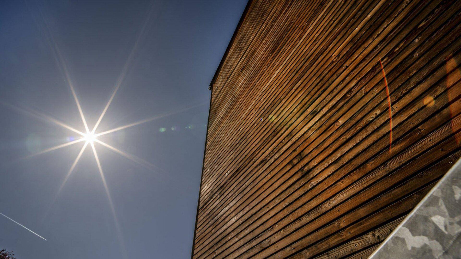 Detailaufnahme einer modernen Holzfassade unter strahlendem Sonnenschein.