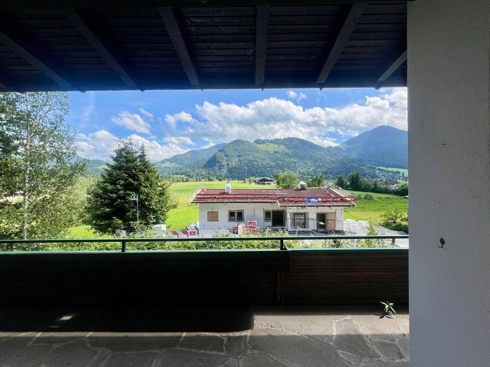 Balkon mit beeindruckendem Ausblick auf die umliegenden Berge und ein Neubauprojekt.
