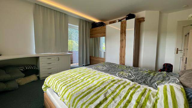 Gemütliches Schlafzimmer mit Doppelbett, Einbauschrank und indirekter Deckenbeleuchtung.