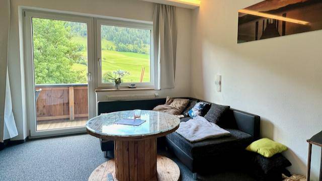 Helles Wohnzimmer mit Ecksofa, Couchtisch und Zugang zu einem Balkon mit Bergblick.