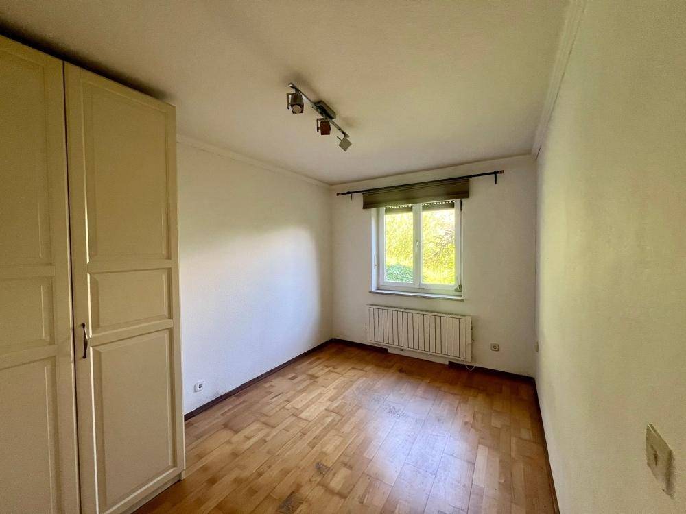 Schlafzimmer mit Holzboden, einem Kleiderschrank und einem Fenster mit Blick nach draußen.