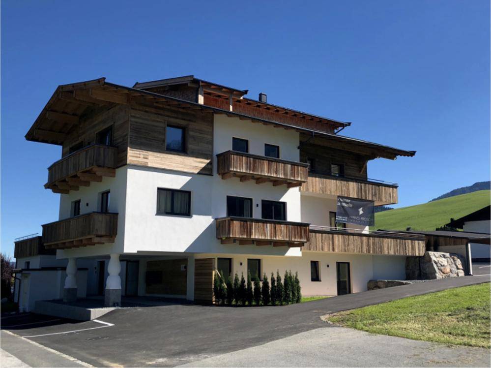 Attraktives Mehrfamilienhaus im alpinen Stil mit Holzfassade und Balkonen in sonniger Lage.