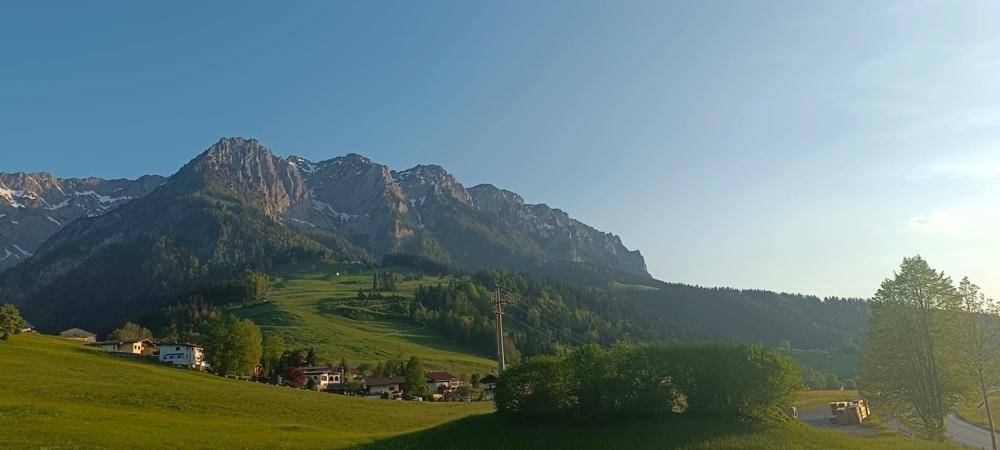 Weitläufiger Blick auf die majestätische Berglandschaft mit grünen Hügeln und Wäldern.