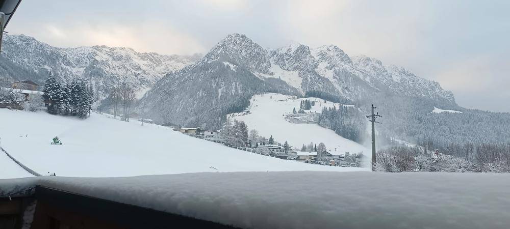 Winterlicher Panoramablick von einem Balkon auf schneebedeckte Berge und Täler.