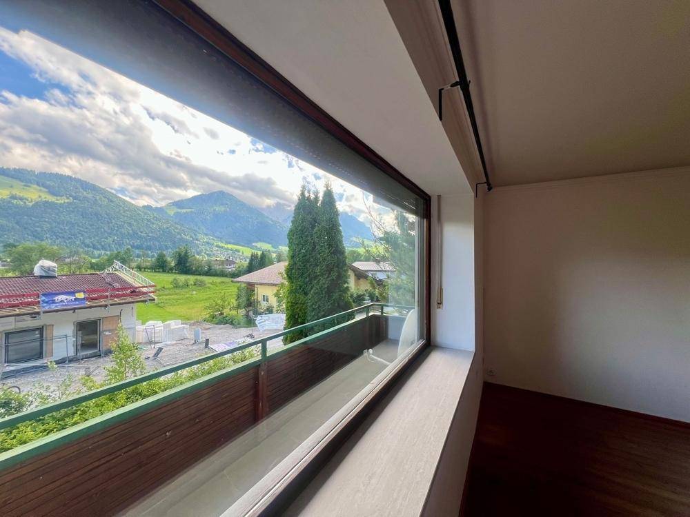 Heller Raum mit großem Fenster, das einen weiten Blick auf die grüne Berglandschaft bietet.