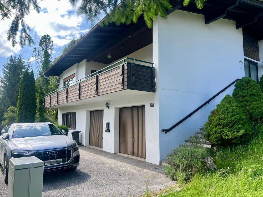 Vorderansicht des Hauses mit zwei Garagen, Auffahrt und einer Außentreppe zum Eingangsbereich.
