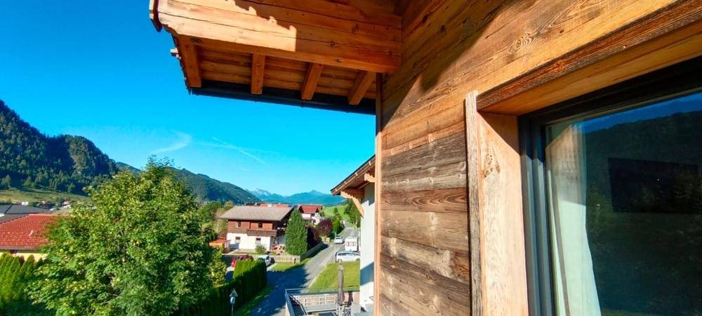 Blick aus dem Fenster auf die umliegende Landschaft mit traditionellen Häusern und Bergen.