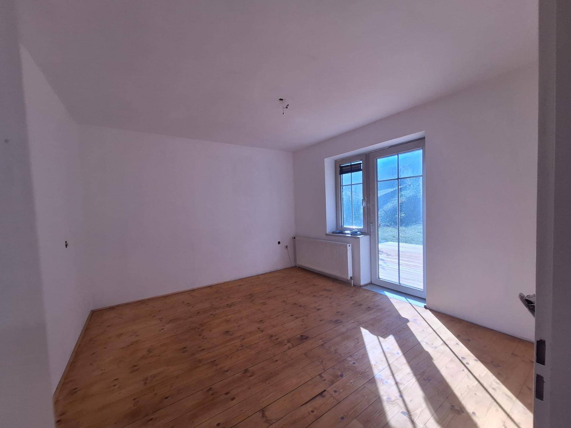 Heller Raum mit Holzdielenboden und direktem Zugang zur Außenterrasse, sonnendurchflutet.