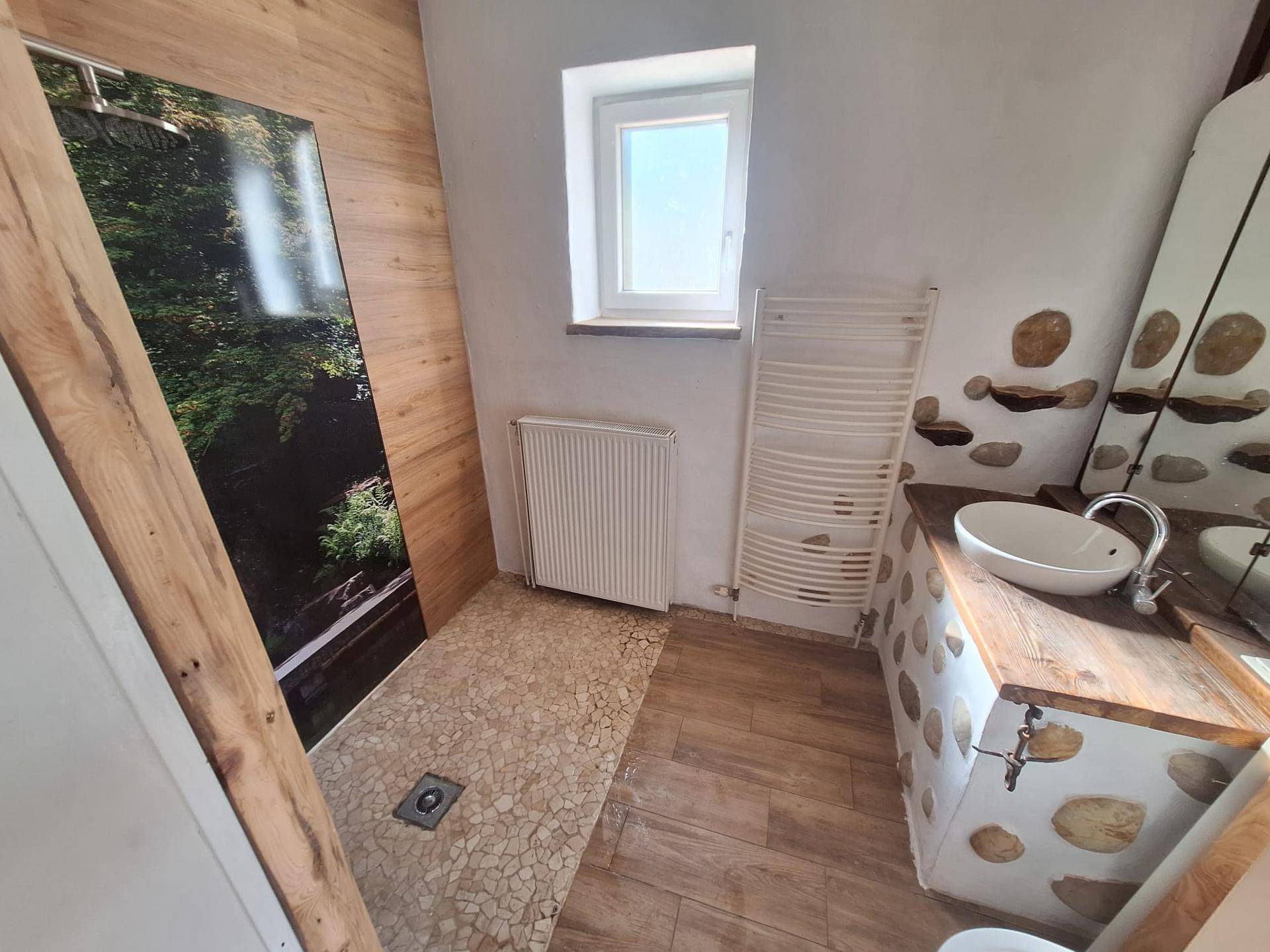 Modernes Badezimmer mit begehbarer Dusche, Holzwaschtisch und beheiztem Handtuchhalter.