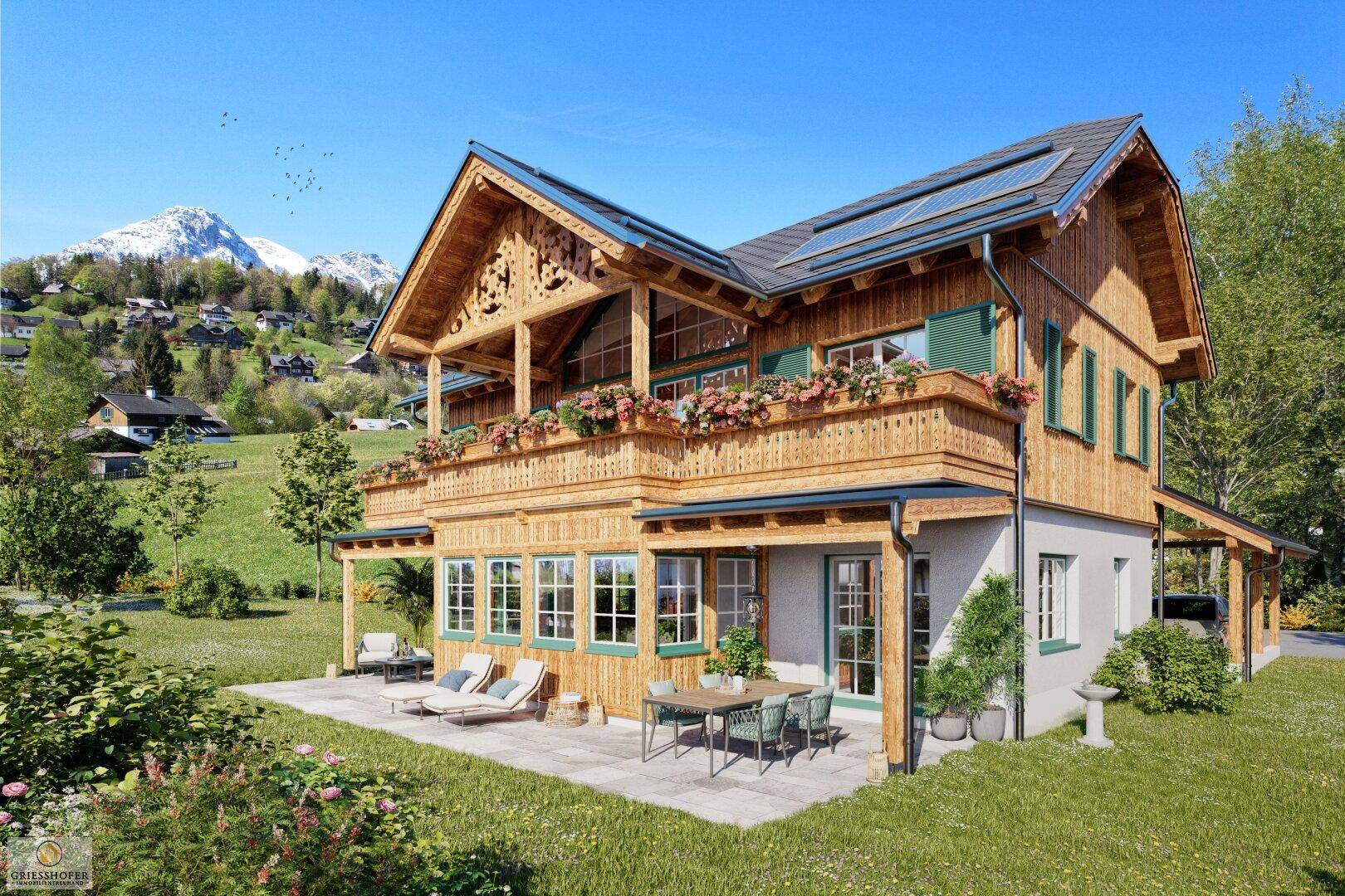 Traditionelles Holzhaus im alpinen Stil mit Balkonen, Terrasse und Photovoltaikanlage vor Bergkulisse.