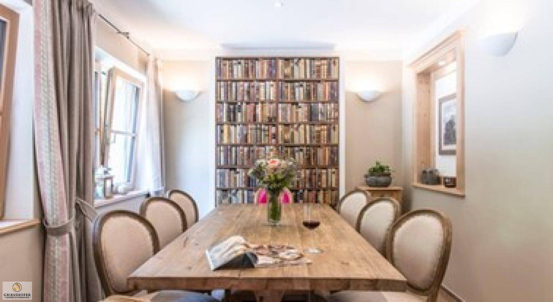 Esszimmer mit großem Holztisch, Bücherregal und traditioneller Einrichtung.