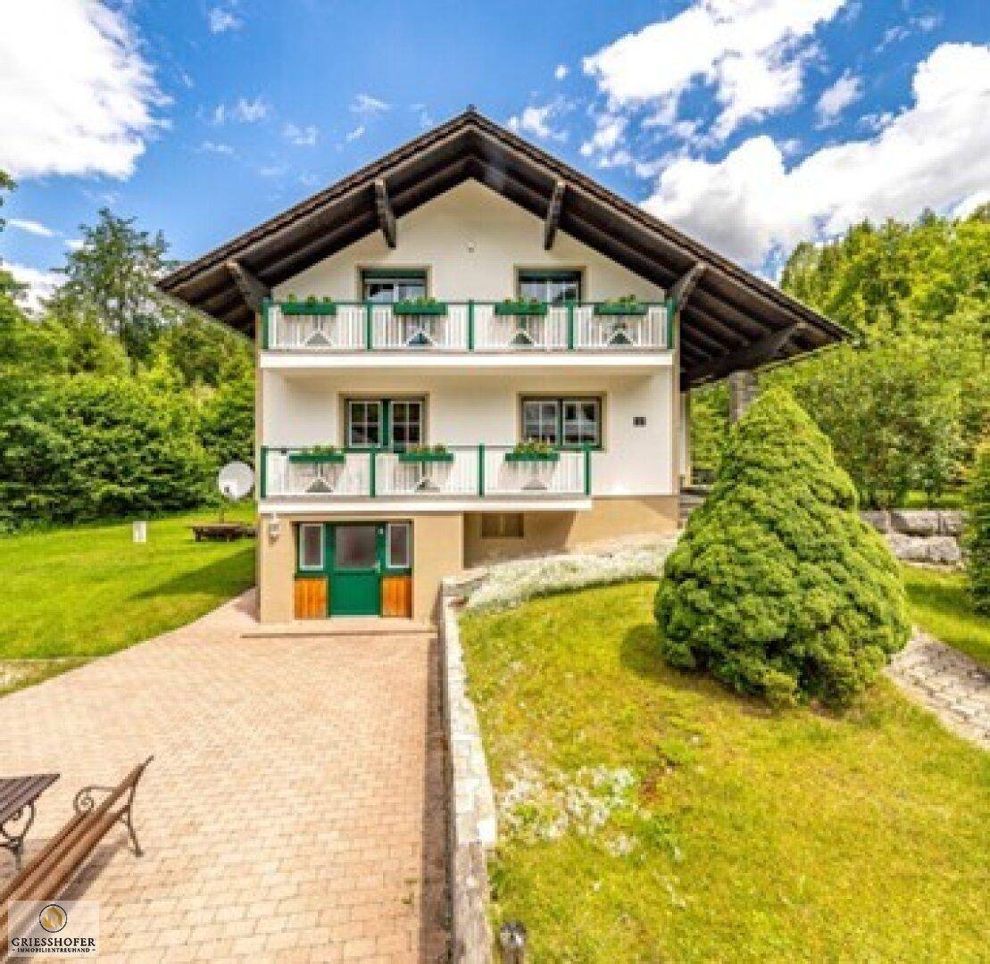 Freistehendes Haus mit Balkonen, gepflasterter Auffahrt und gepflegtem Garten.