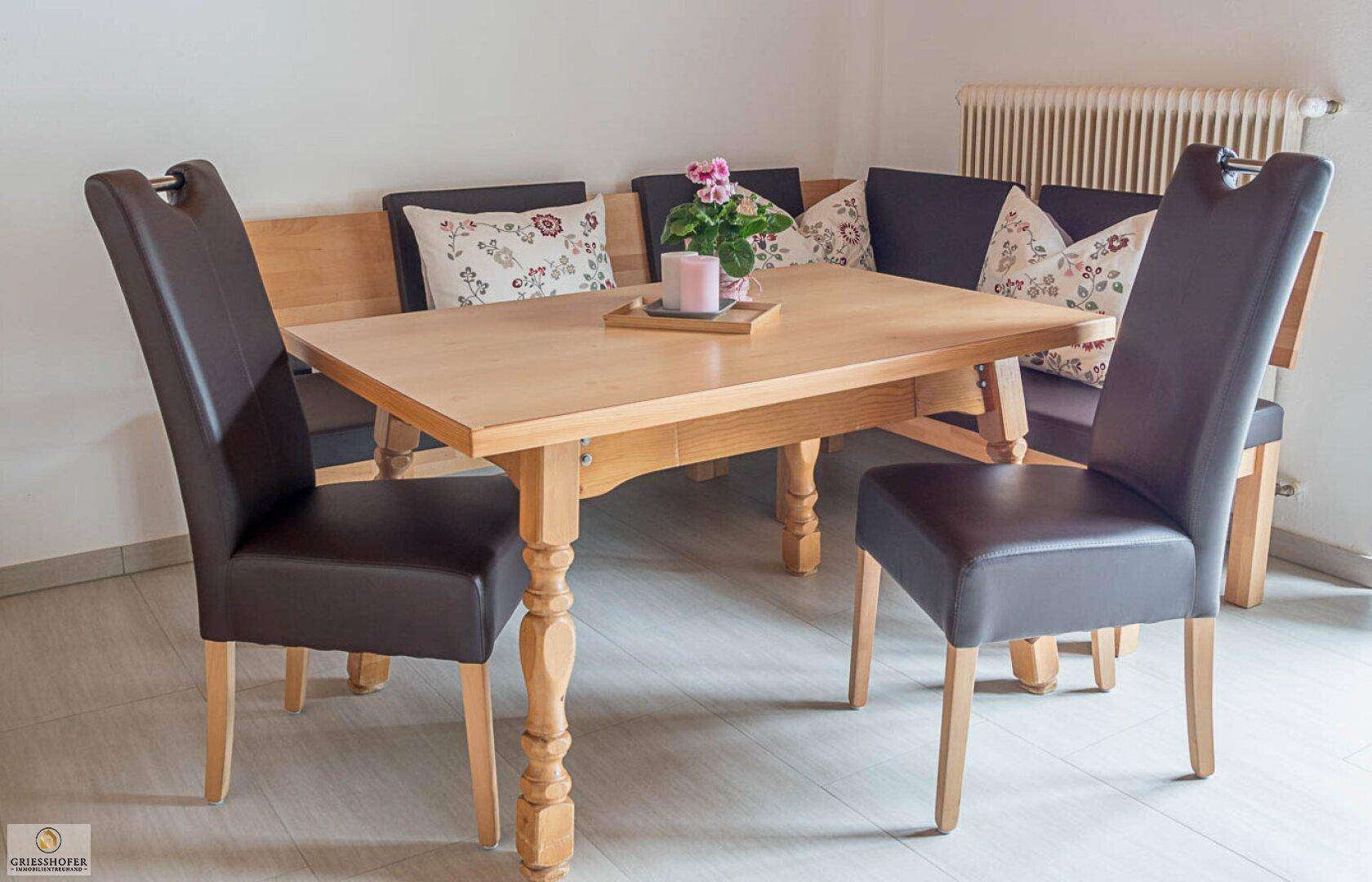 Gemütlicher Essbereich mit Holztisch, Eckbank und dunklen Lederstühlen.