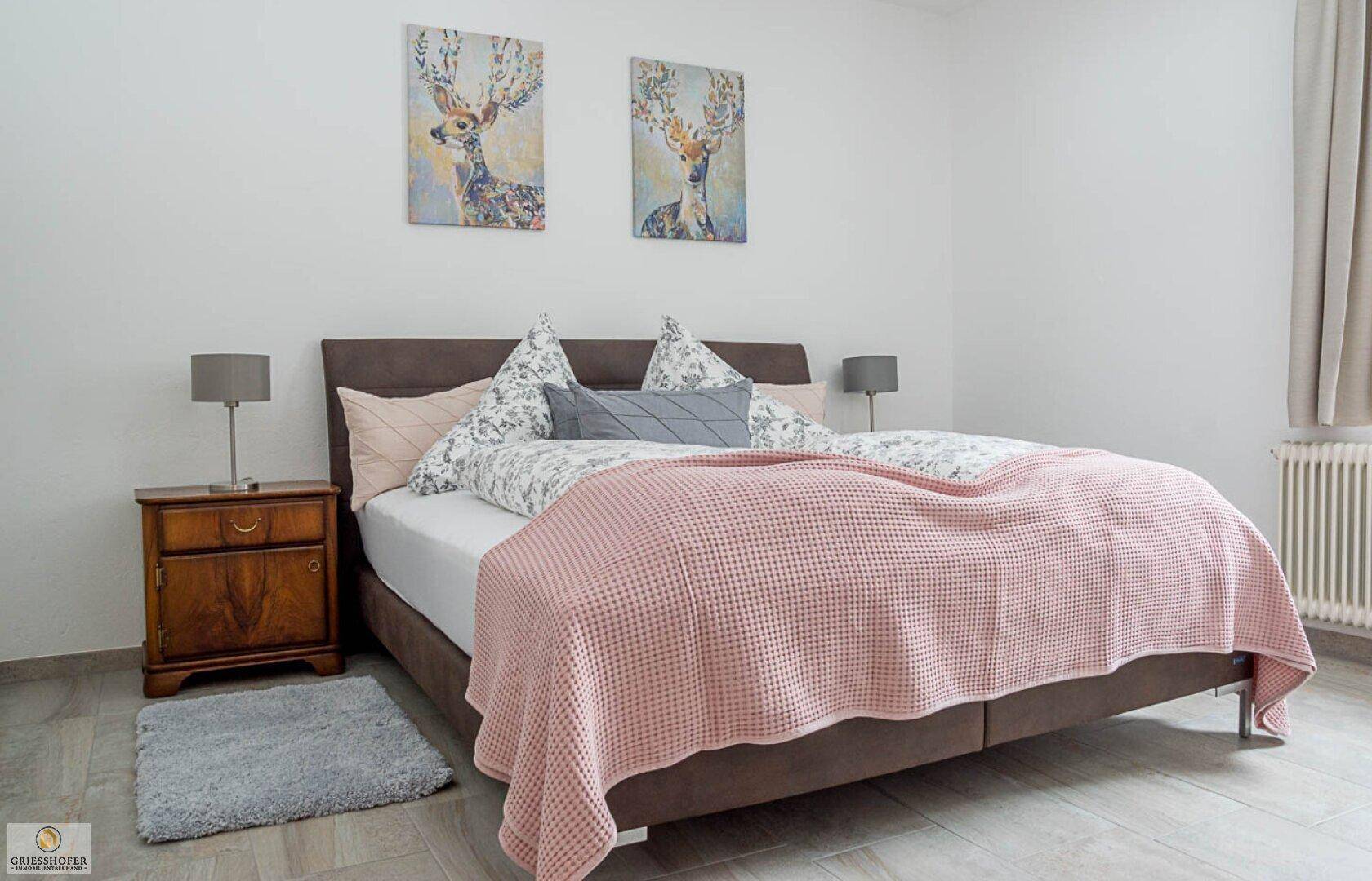 Schlafzimmer mit Doppelbett, Nachttischen und Hirschmotiven an der Wand.