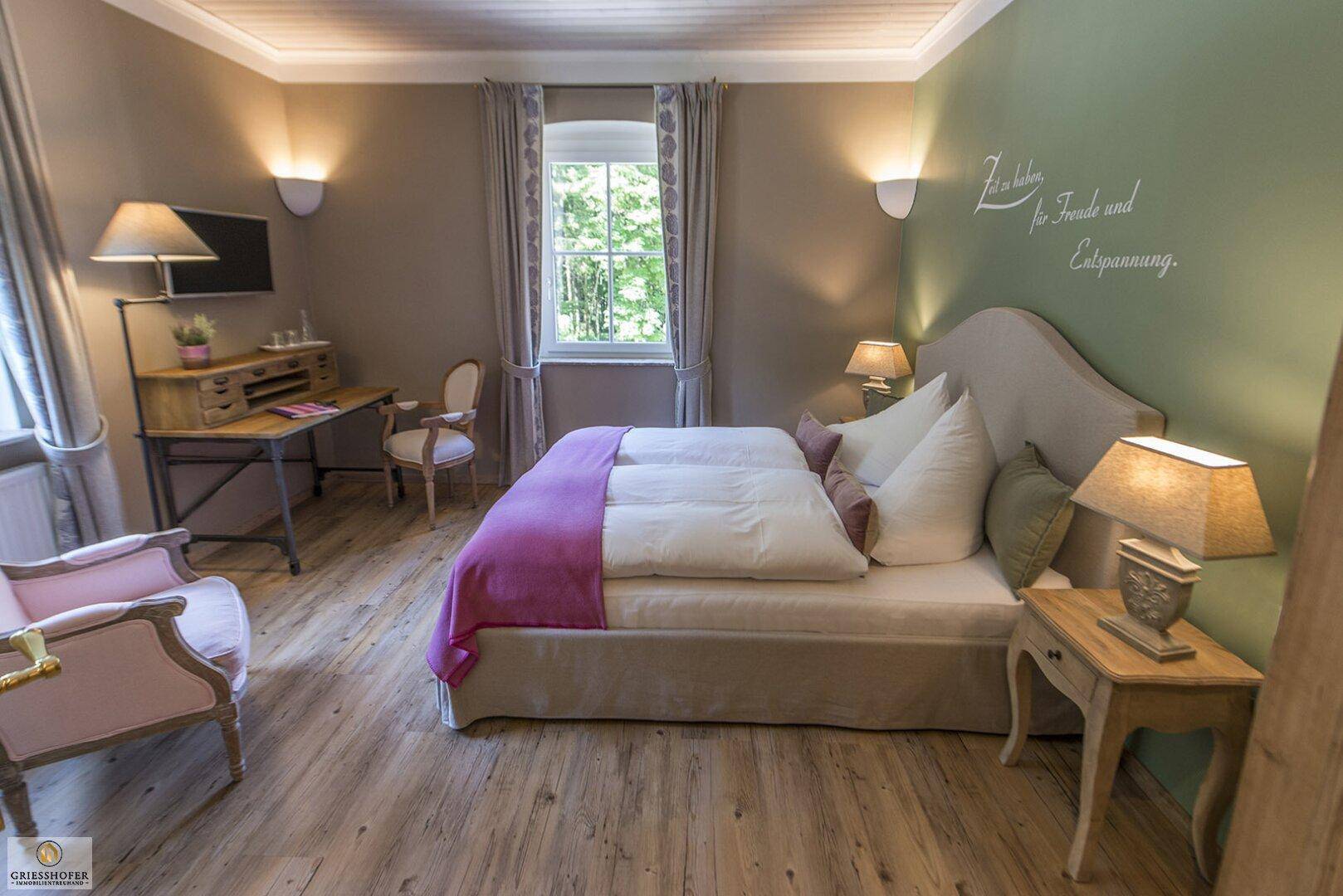 Helles Schlafzimmer mit Doppelbett, Schreibtisch und Blick ins Grüne.