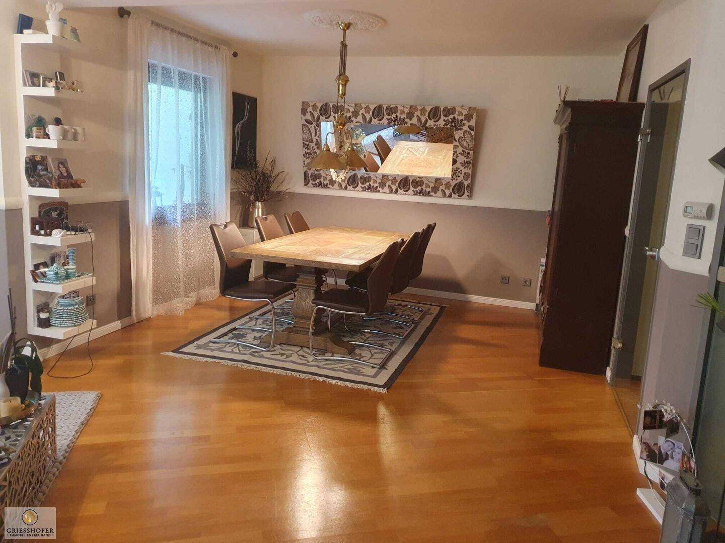 Essbereich mit Holztisch, passenden Stühlen und dekorativem Spiegel an der Wand.