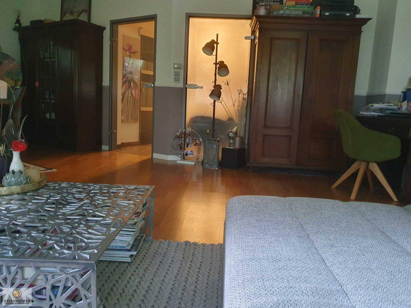 Blick vom Wohnbereich auf den Flur mit Holztüren und einem dekorativen Stehlampen-Arrangement.