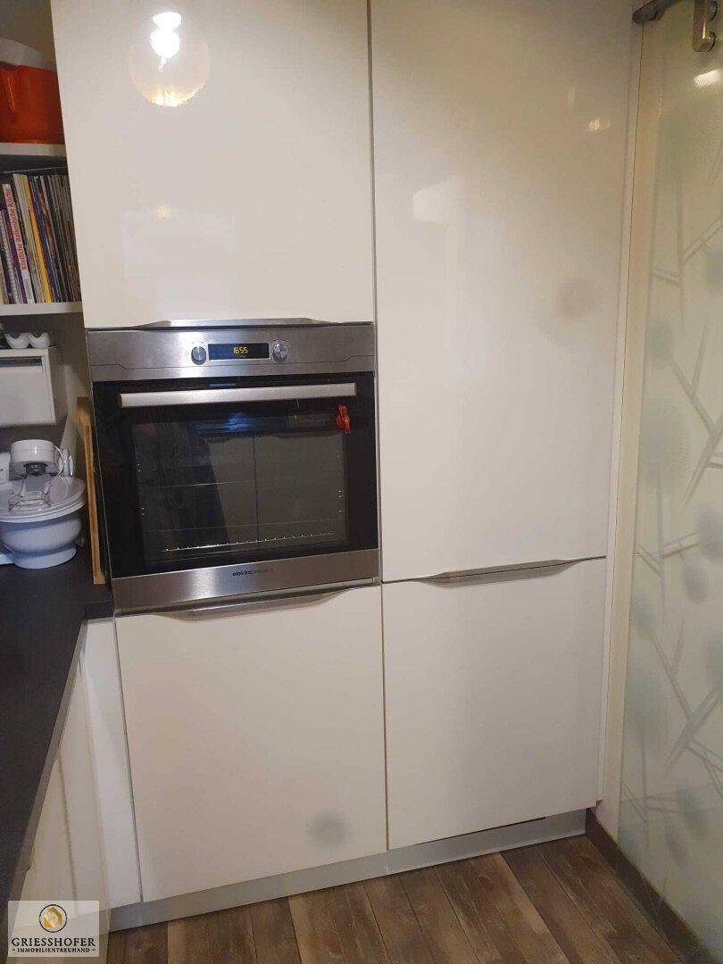 Integrierter Backofen in der modernen Küche mit weißen Hochglanzfronten und dunkler Arbeitsplatte.