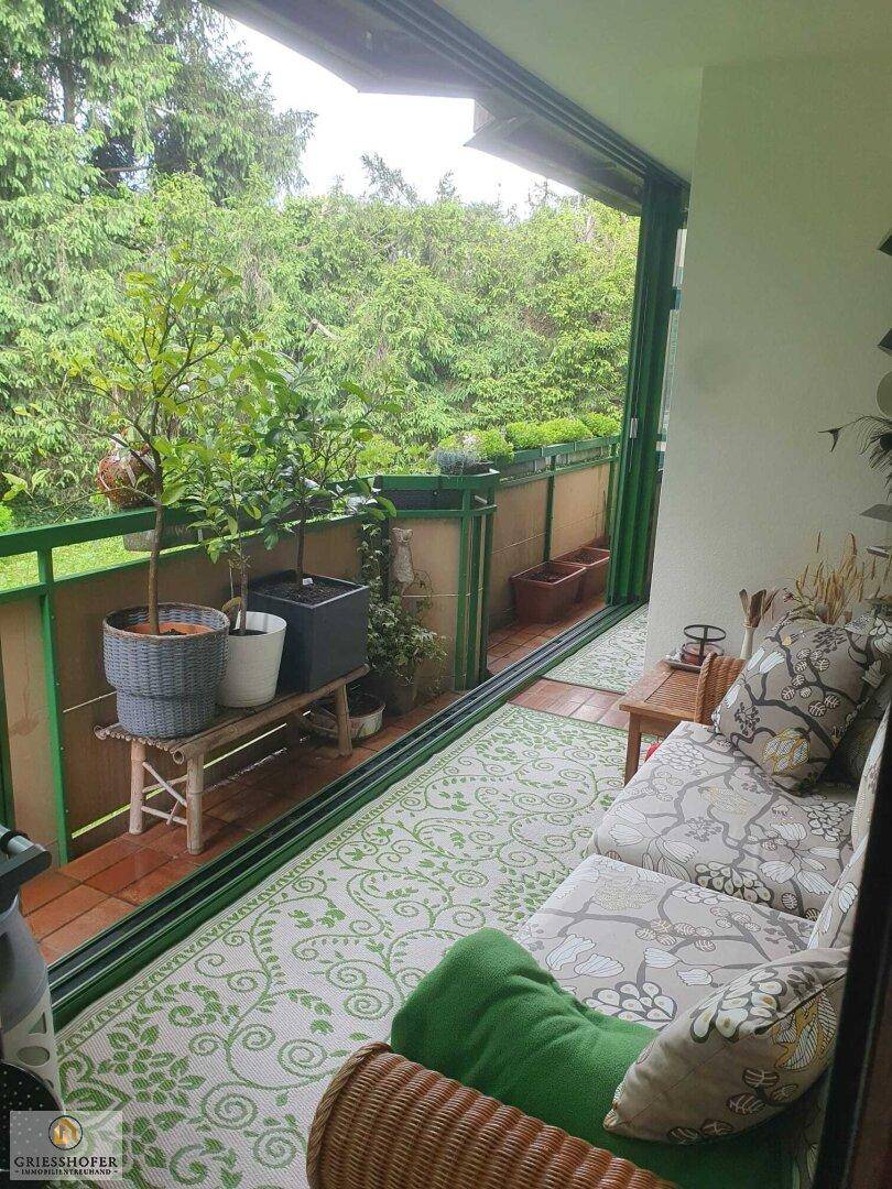 Gemütliche verglaste Loggia mit Sitzgelegenheiten und üppigem Grünblick.