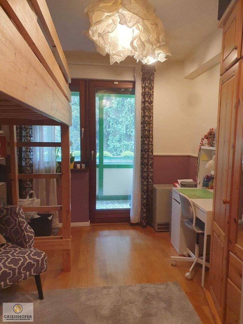 Kinderzimmer mit Hochbett, Schreibtisch und Zugang zu einem kleinen Balkon.