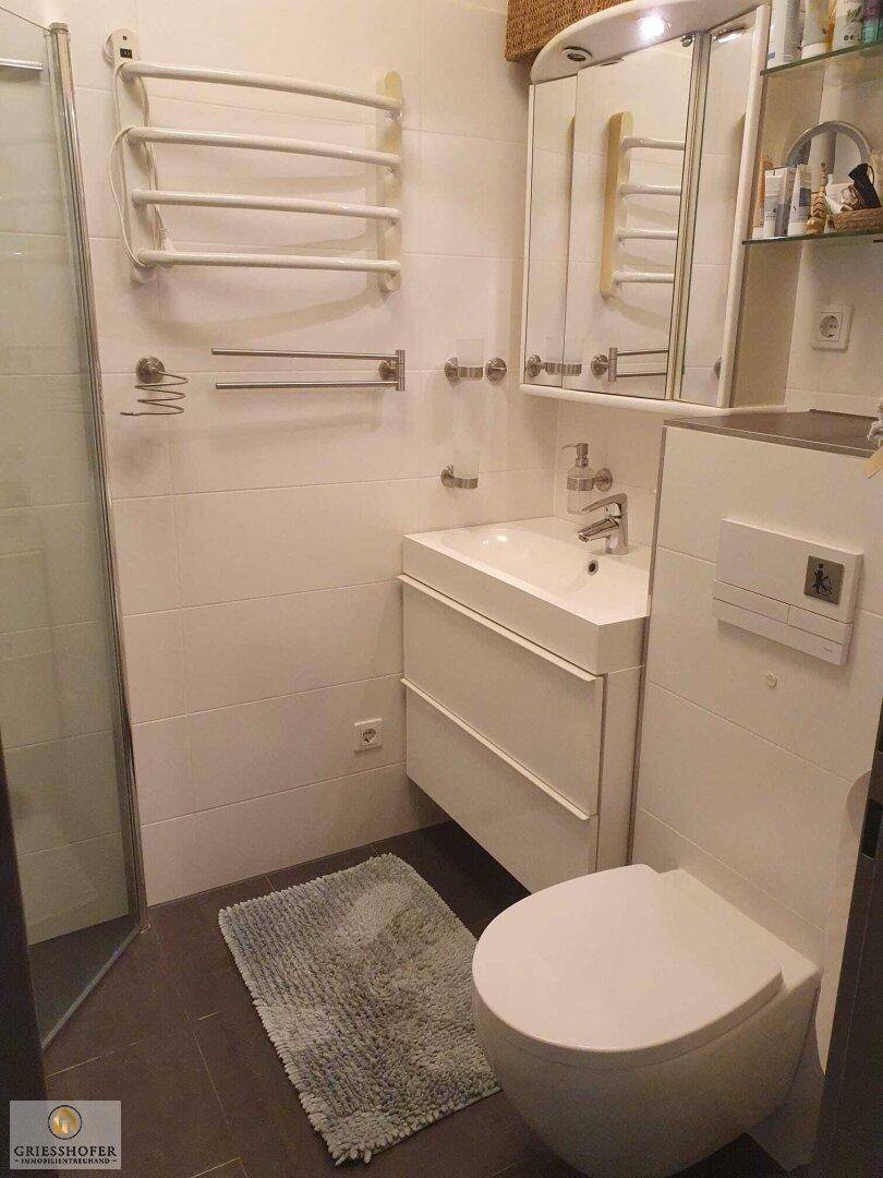 Helles Badezimmer mit modernem Waschtisch, WC und Spiegelschrank.