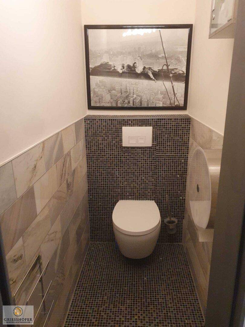 Separate Gästetoilette mit modernen Mosaikfliesen und Wand-WC.