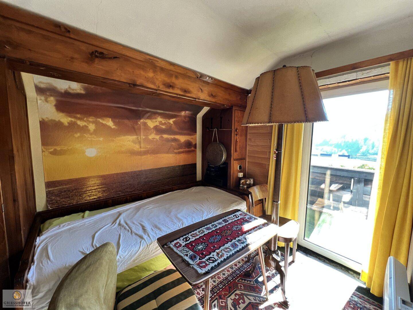 Gemütliches Schlafzimmer mit Holzwänden, Einzelbett und großem Fenster mit Ausblick.