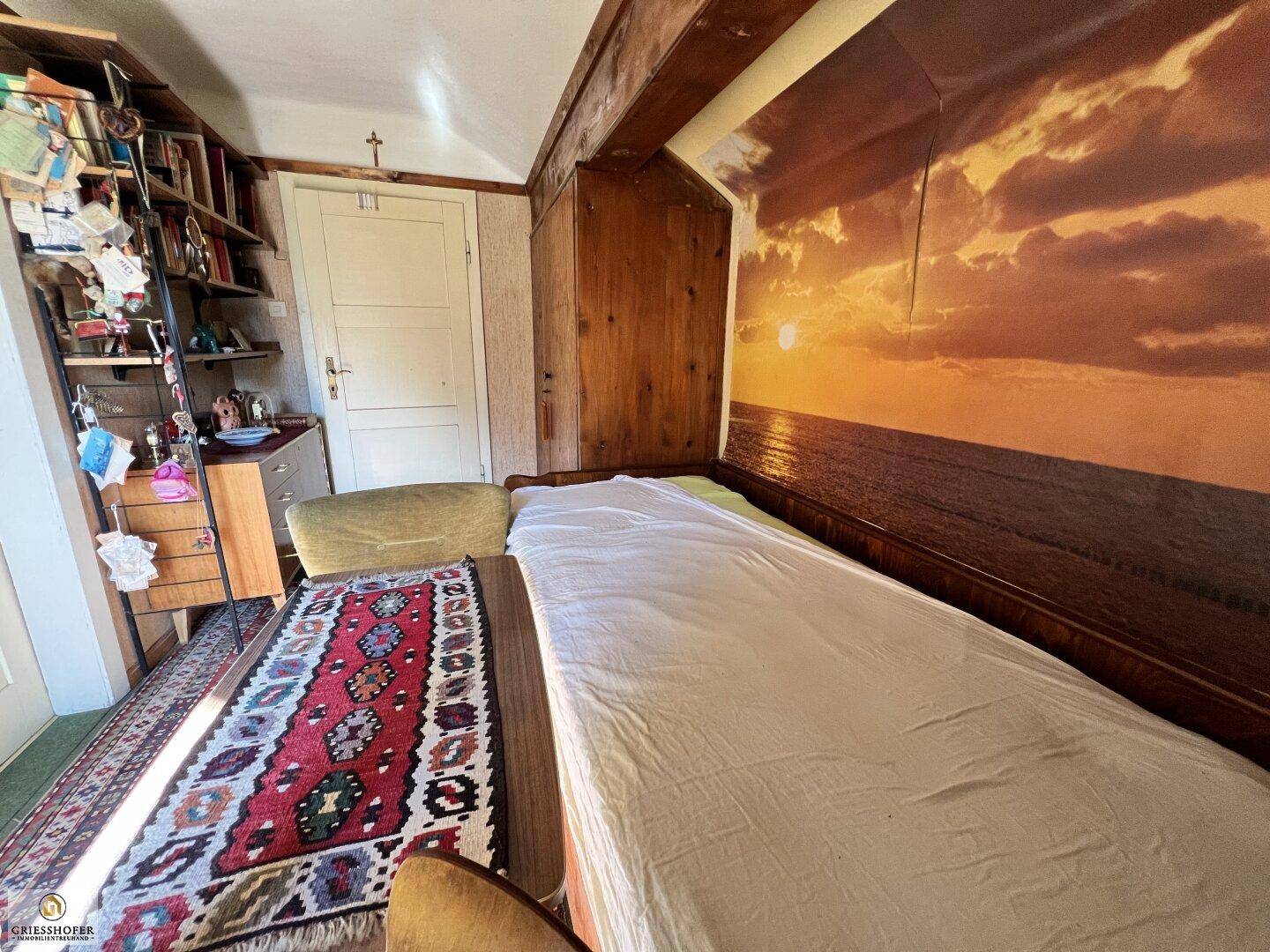 Helles Schlafzimmer mit Holzwänden, Einzelbett und Bücherregal.