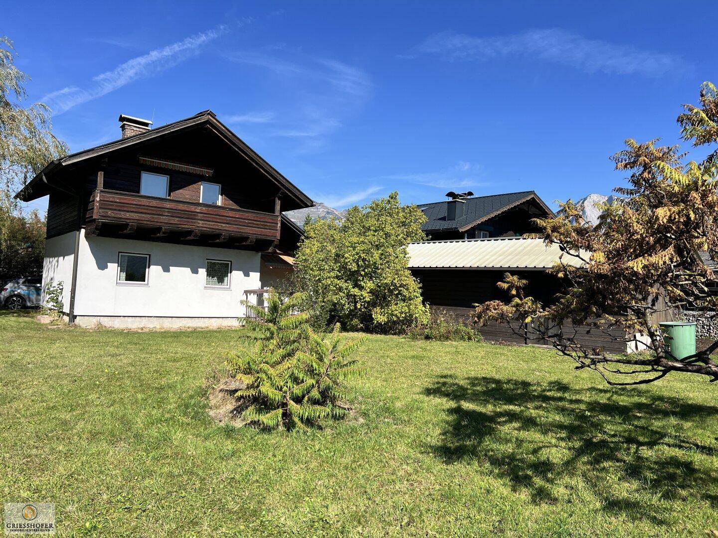 Traditionelles Haus mit Holzbalkon und großem grünen Gartenbereich.