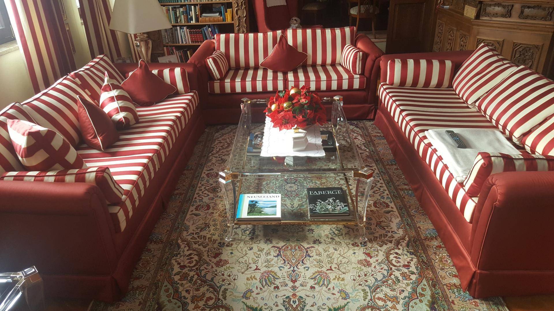 Gemütliches Wohnzimmer mit roten gestreiften Sofas, einem Glastisch und einem orientalischen Teppich.