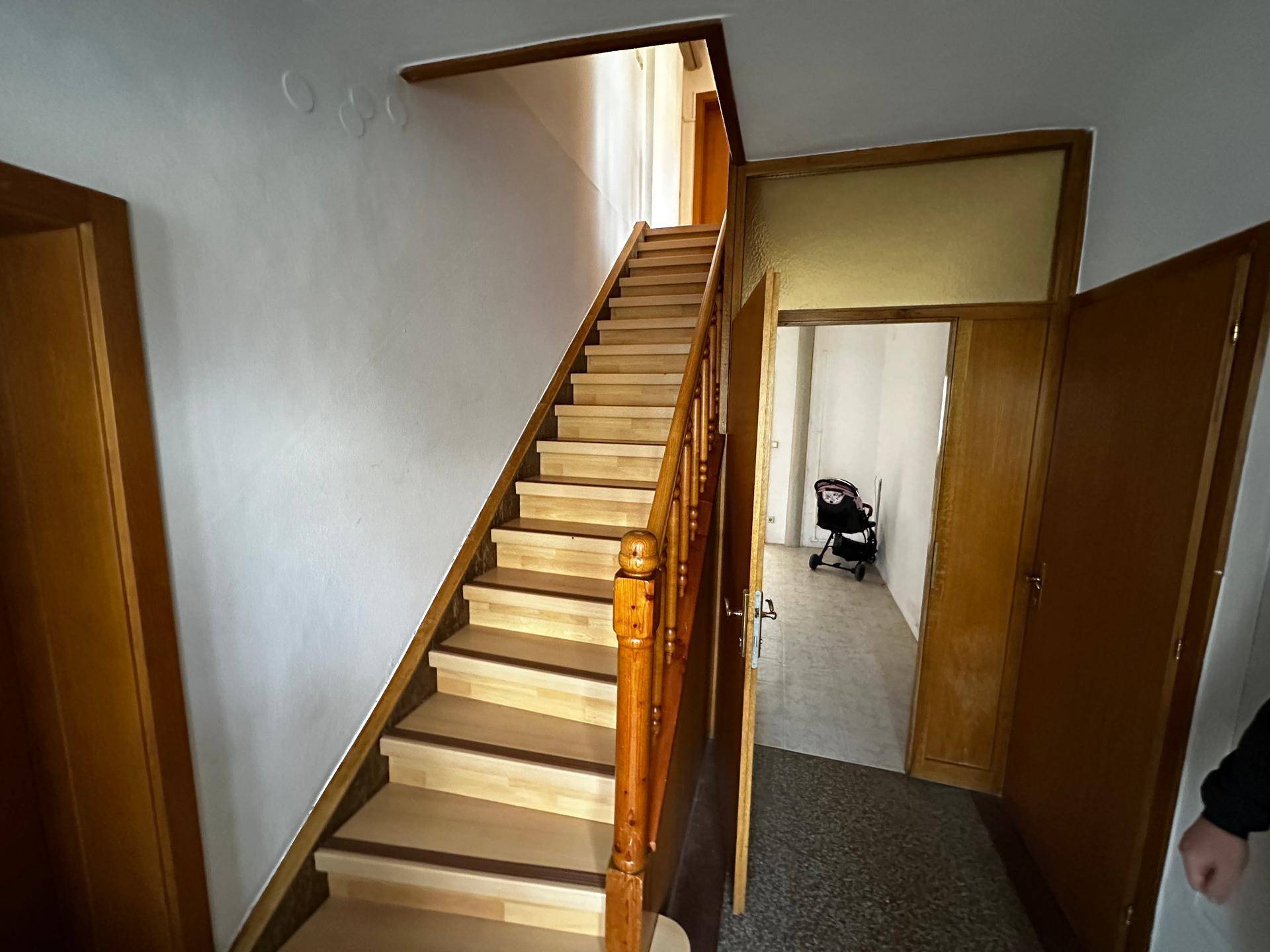 Heller Flur mit Holztreppe, die in die oberen Stockwerke führt, und Holztüren.