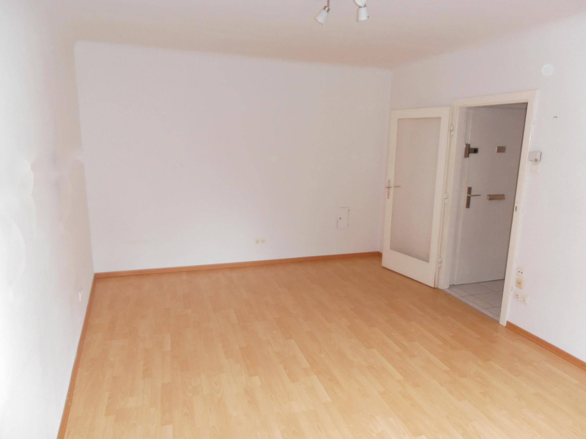 Geräumiges Wohnzimmer mit Laminatboden und weiß gestrichenen Wänden.