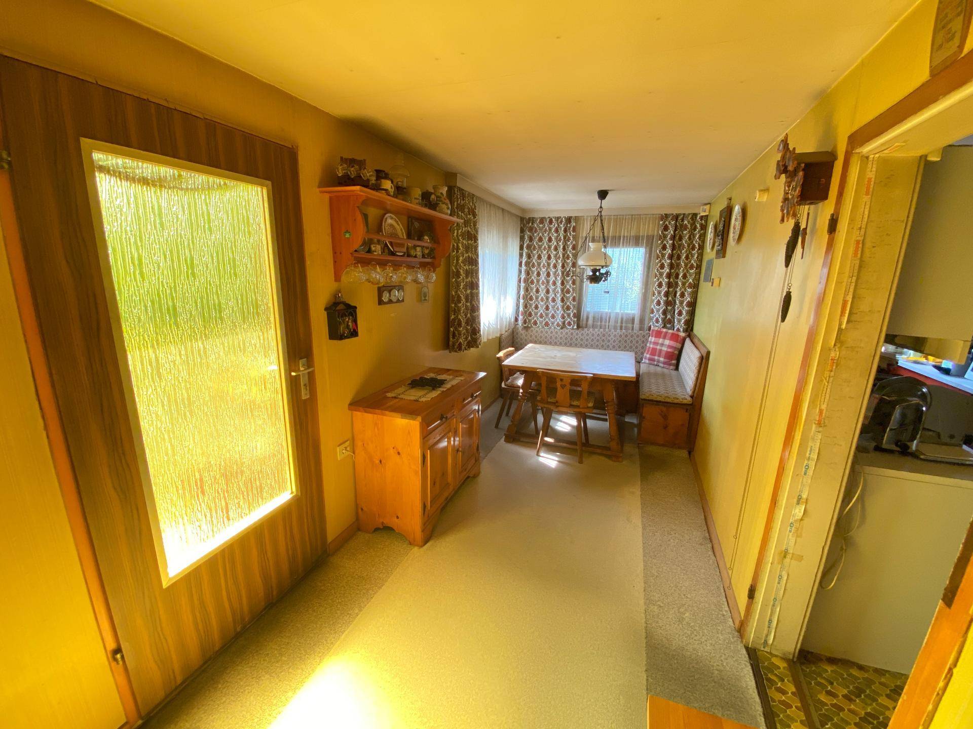 Traditioneller Essbereich mit Holztisch, Eckbank und rustikalen Holzmöbeln, durchflutet von natürlichem Licht.