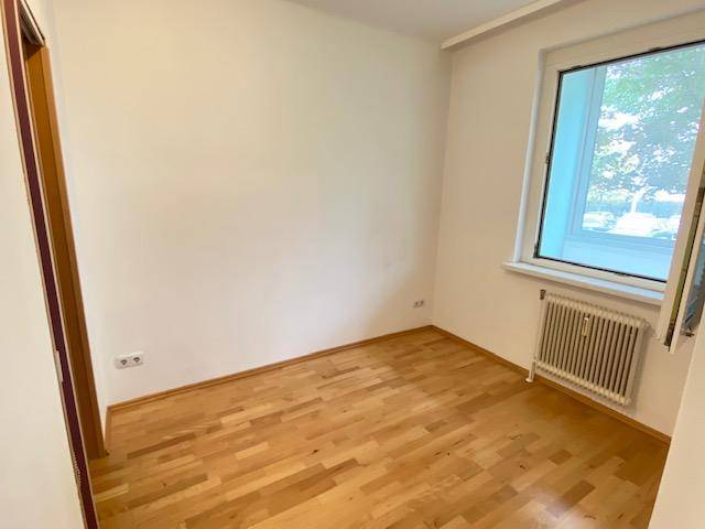 Helles Schlafzimmer mit Parkettboden und Fenster, bietet eine ruhige Atmosphäre.