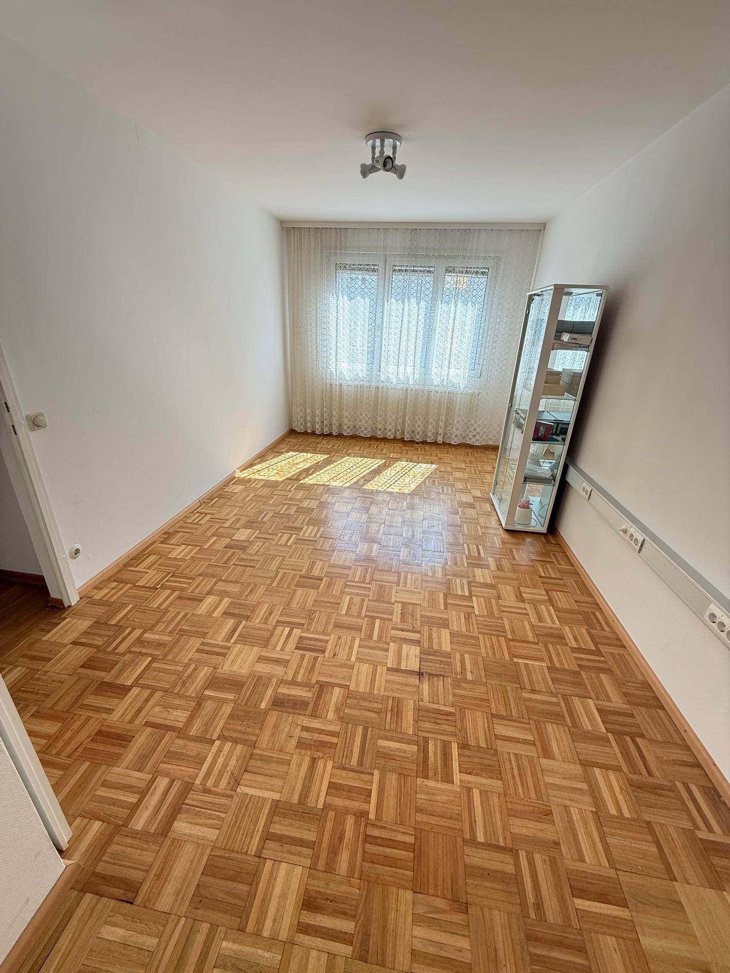 Geräumiges Schlafzimmer mit Parkettboden, hellen Wänden und viel Tageslicht durch die Fenster.