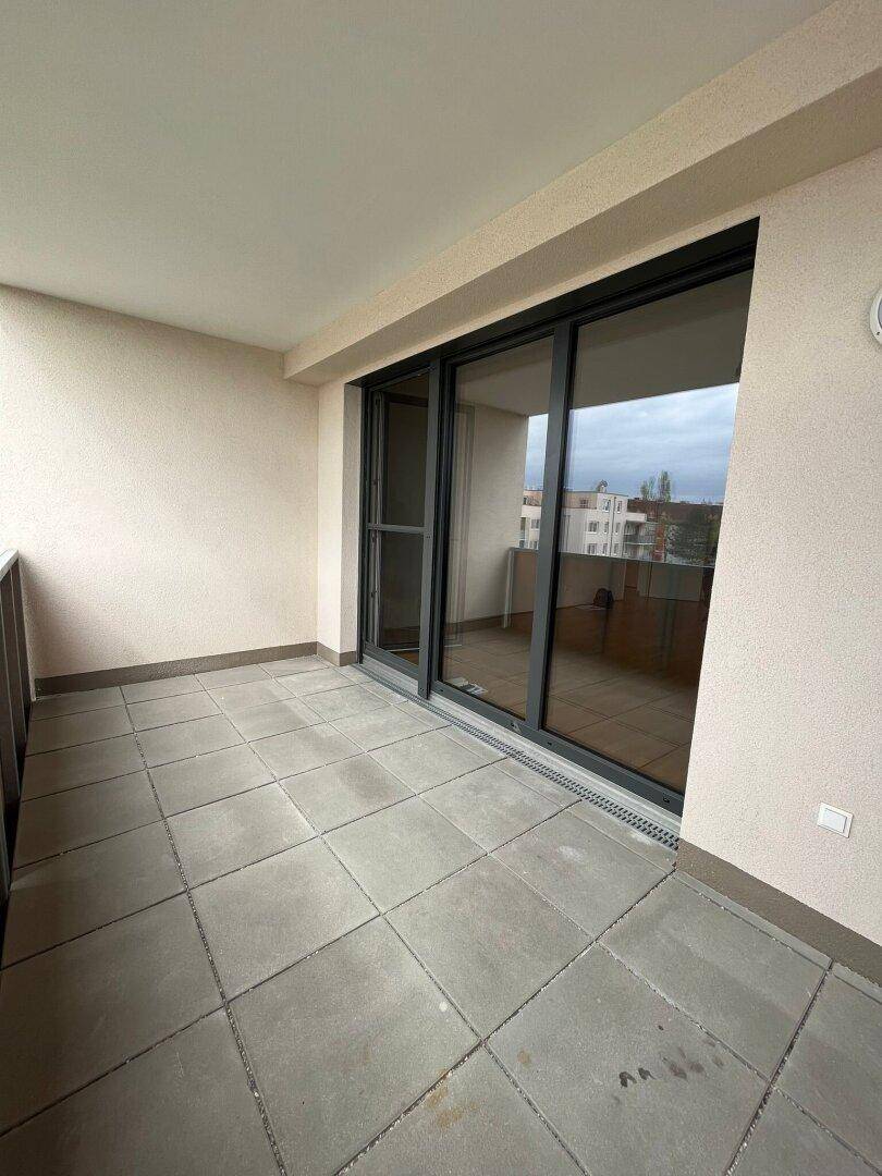 Geräumiger Balkon mit Fliesenboden und Schiebetüren, bietet Platz für Entspannung im Freien.