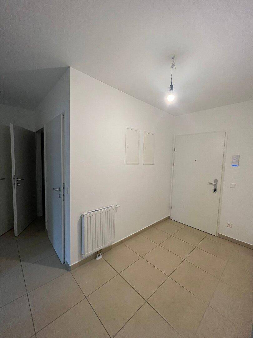 Eingangsbereich mit Fliesenboden, weißen Wänden und Heizkörper, der zu weiteren Räumen führt.