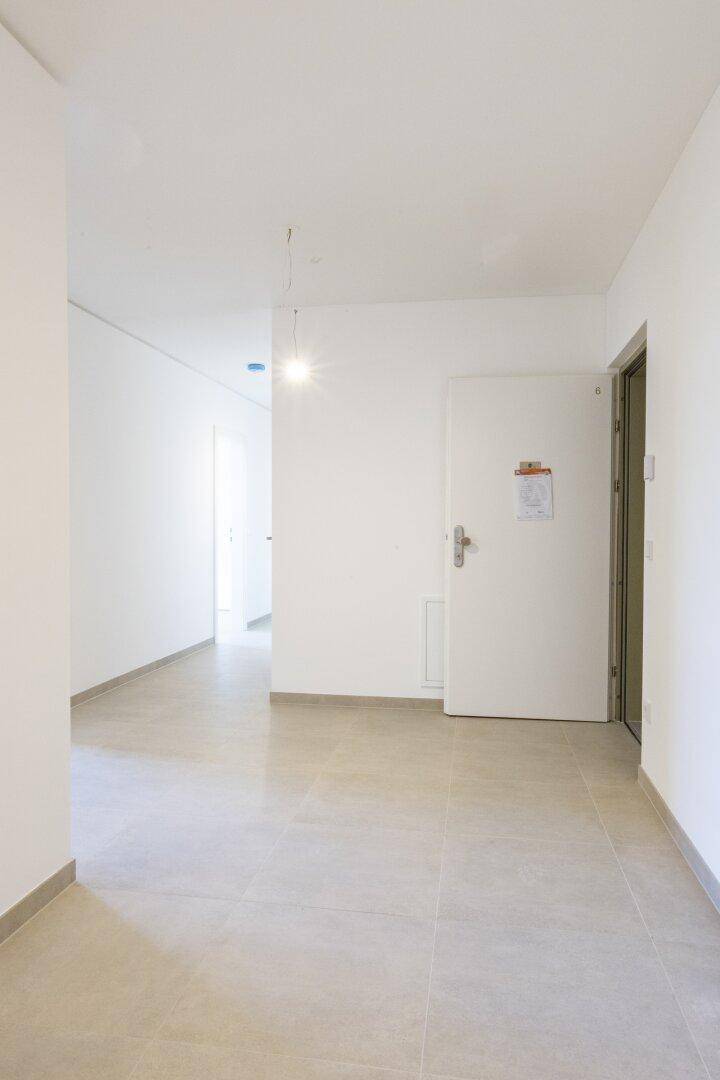 Geräumiger, heller Flur mit Fliesenboden und weiß gestrichenen Wänden.
