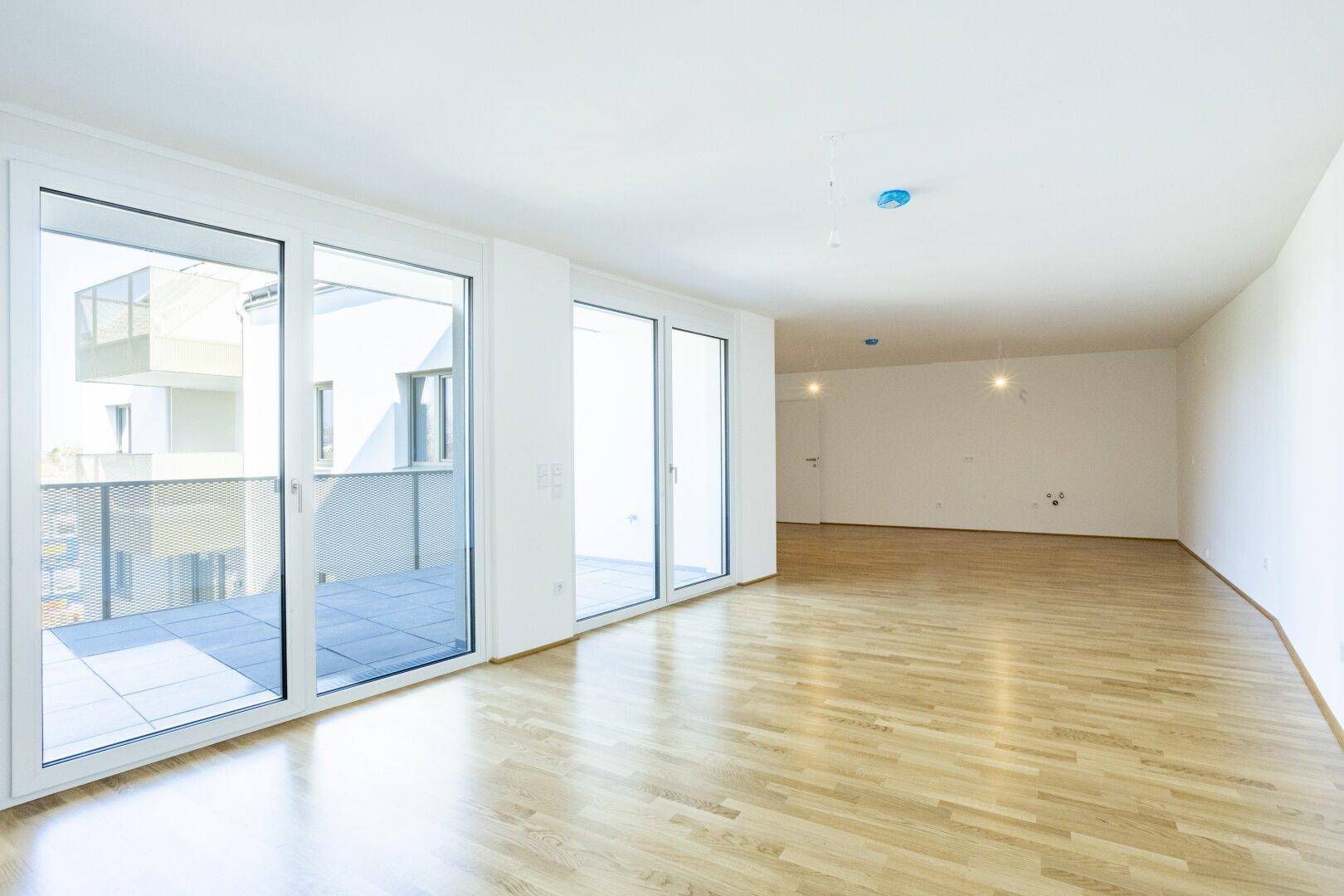 Lichtdurchfluteter Wohnbereich mit Parkettboden und Zugang zum Balkon, bietet viel Platz.