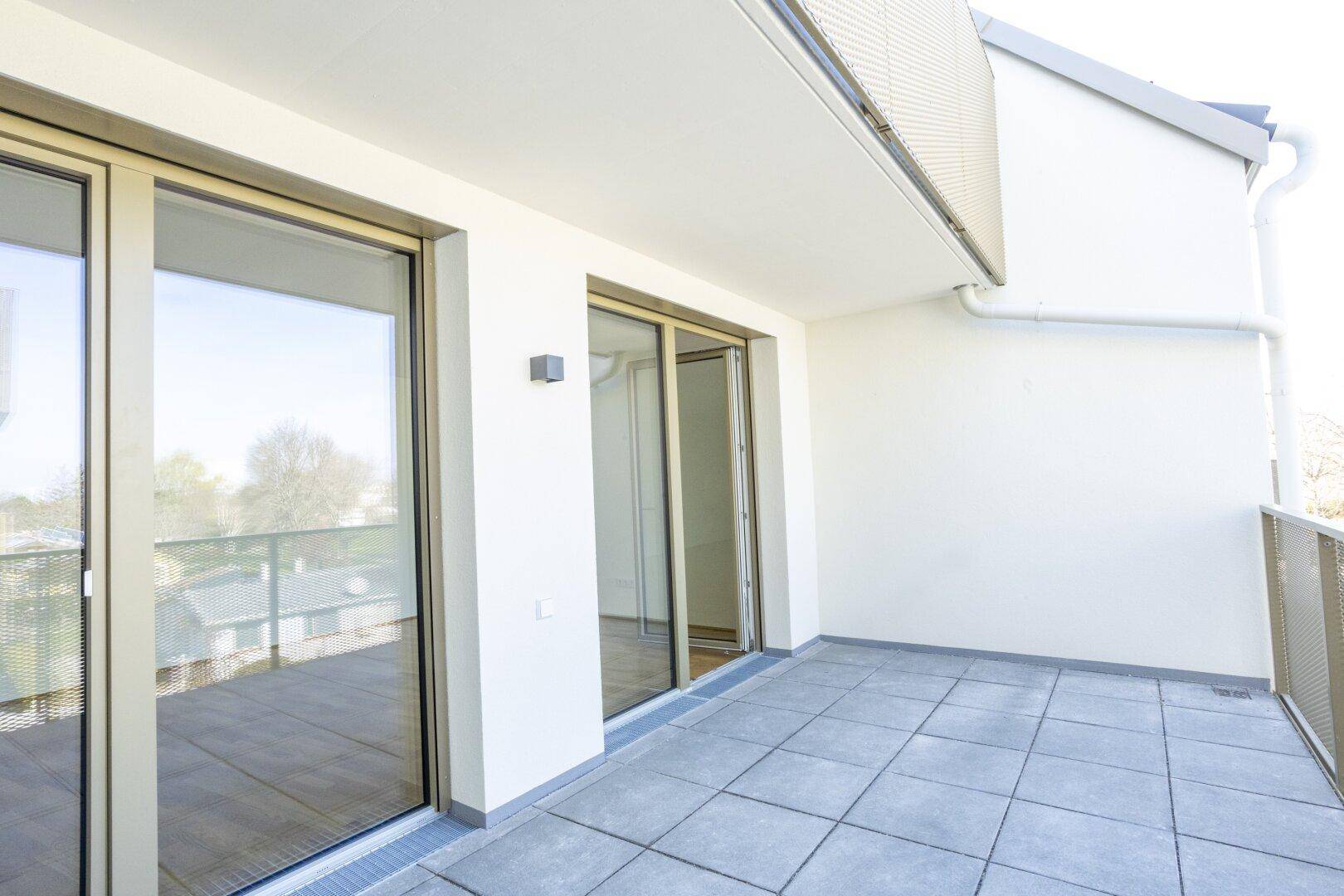 Heller Balkon mit Fliesenboden und Blick ins Grüne, ideal für entspannte Stunden.