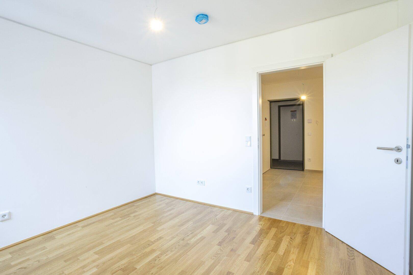 Schlafzimmer mit Parkettboden und weiß gestrichenen Wänden, bereit zur individuellen Gestaltung.