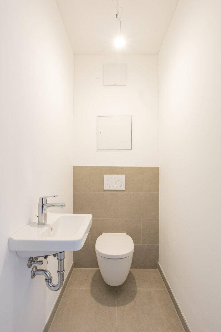 Separates WC mit wandhängendem WC und kleinem Waschbecken, in modernem Design.